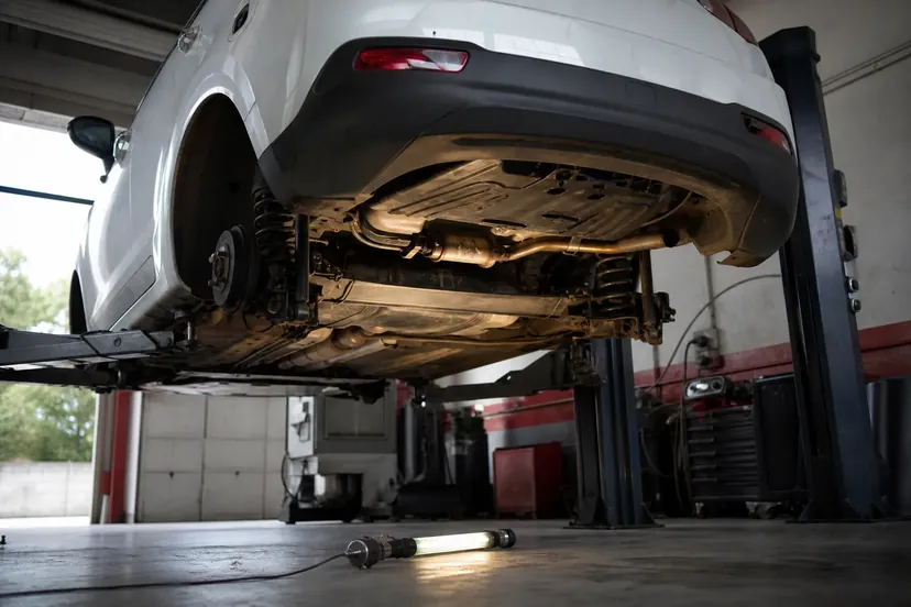 Citroën C3 levée sur un pont élévateur, ligne d'échappement vue de dessous dans un atelier