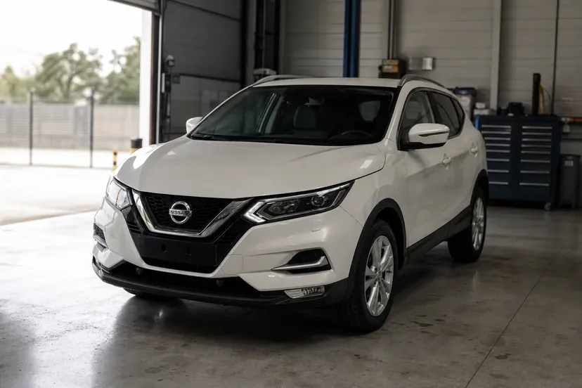 Nissan Qashqai de deuxième génération blanc nacré, vu de trois quarts avant, immobile dans une travée d'atelier.