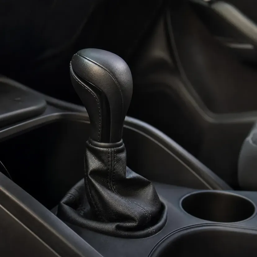 Levier de sélection d'une boîte automatique gainé de cuir noir, vu de près dans un habitacle vide, sans inscription visible.