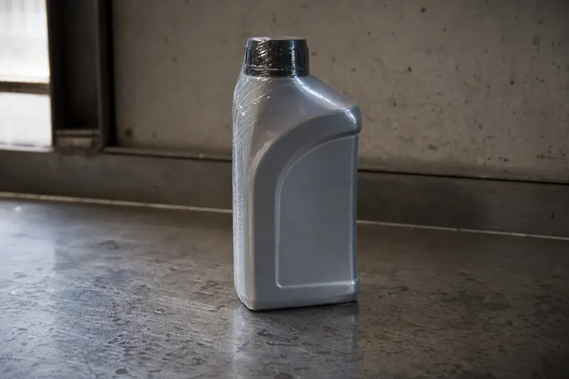 Un bidon de liquide de frein encore scellé, posé seul sur l'établi d'un atelier automobile.
