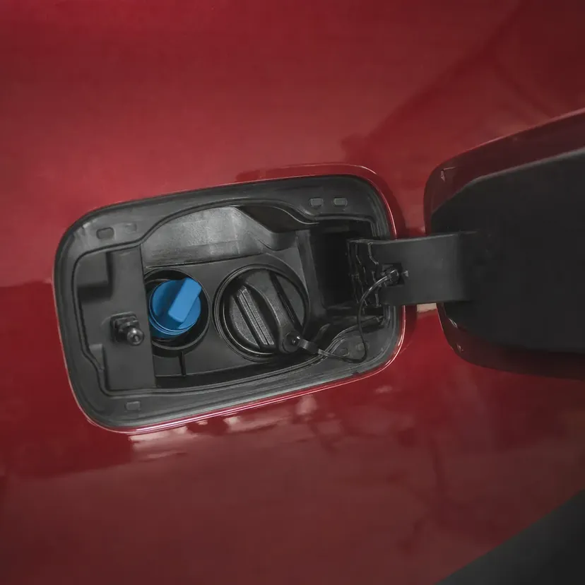 La trappe de remplissage ouverte d'une voiture, bouchon de carburant et bouchon bleu d'AdBlue côte à côte.