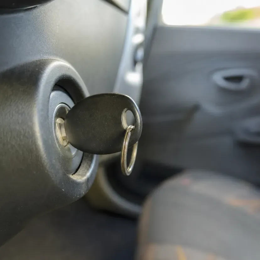 Une clé de contact engagée dans le contacteur-démarreur d'une voiture, vue de près dans l'habitacle.