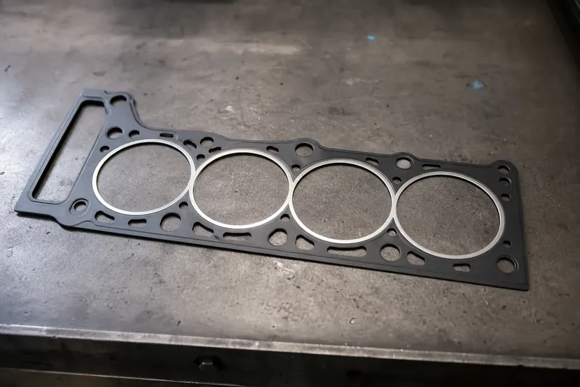 Un joint de culasse neuf posé à plat sur l'établi d'un atelier.
